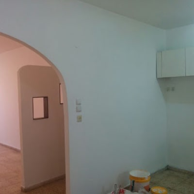 דלי צבע ומברשת על רצפה ליד קיר לבן