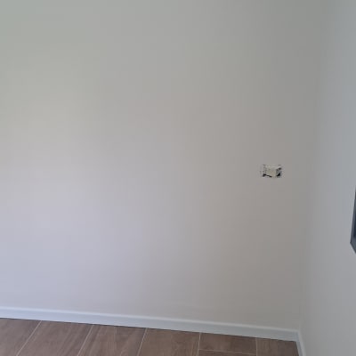 קיר צבוע בלבן עם שקע חשמל חשוף