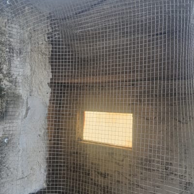 רשת מתכת מותקנת על קיר למניעת כניסת יונים