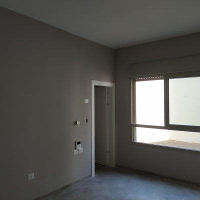 קיר צבוע בגוון אפור בהיר עם חלון גדול