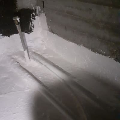 צינורות מתכת עם חומר איטום לבן על קיר בטון