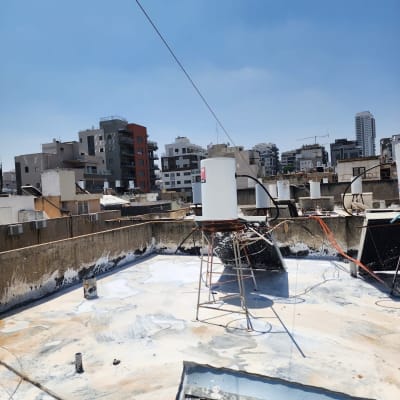 גג עם חומר איטום לבן ומיכל מים