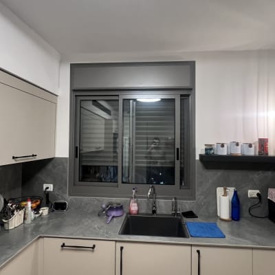 מטבח עם כיור, חומרי ניקוי ומגבת כחולה