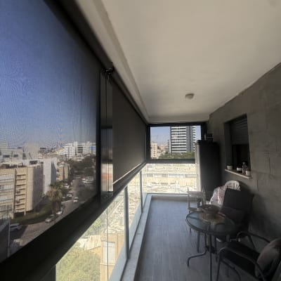 מרפסת עם סוכך נגלל ונוף עירוני