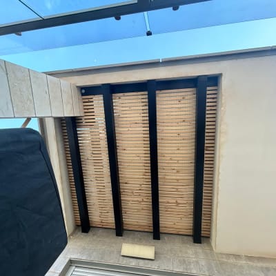 קיר עץ עם קורות מתכת שחורות בגינה