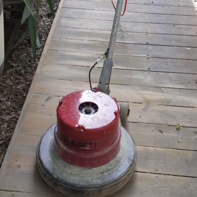 מכונת ליטוש אדומה על שביל עץ בגינה