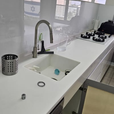 ברז מטבח נשלף וכיור מותקנים על משטח שיש לבן