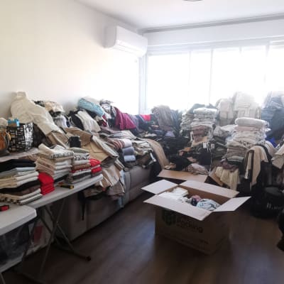 חדר מלא בבגדים מקופלים ומסודרים על שולחנות וספה