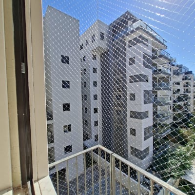 התקנת רשת הגנה מתוחה נגד יונים במרפסת בניין גבוה