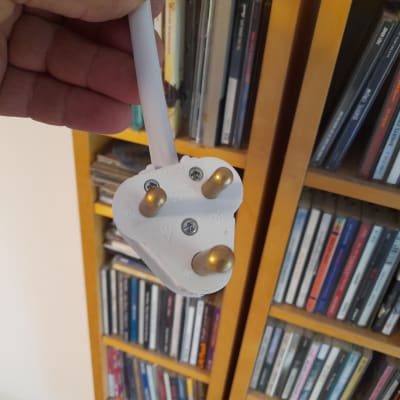 תקע חשמלי לבן עם שלושה פינים ביד אדם