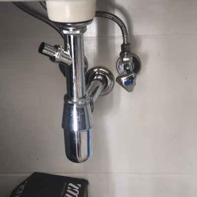 צנרת מתחת לכיור עם ברזים וכבלים