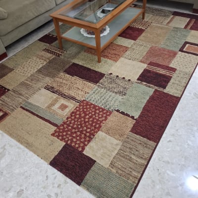 שטיח צבעוני על רצפה ליד ספה ושולחן זכוכית