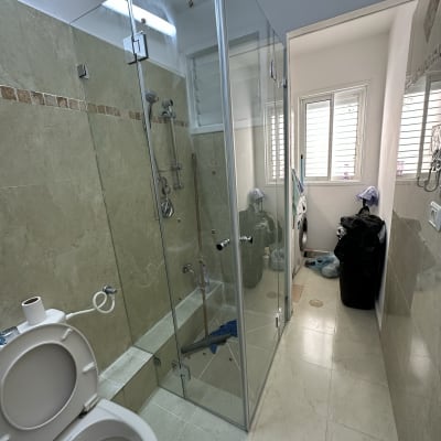 מקלחון זכוכית עם ראש מקלחת וכמה בקבוקים