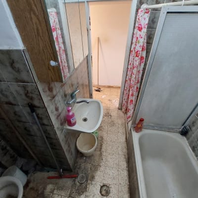 חדר אמבטיה עם כיור, אמבטיה, ודלי על הרצפה