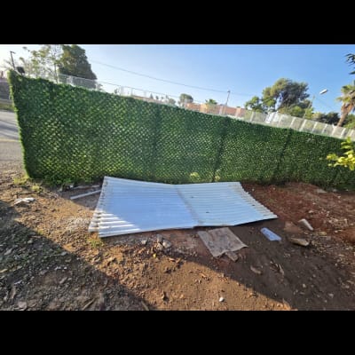 גדר ירוקה עם לוחות מתכת על הקרקע