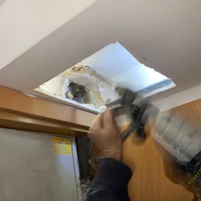 אדם משתמש בכלי עבודה לפתיחת תקרה