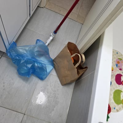 מגב, שקית ניילון כחולה ושקית נייר על רצפת חדר אמבטיה