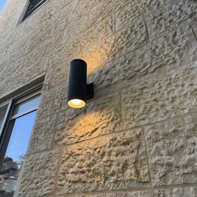 מנורת קיר דולקת על קיר אבן חיצוני