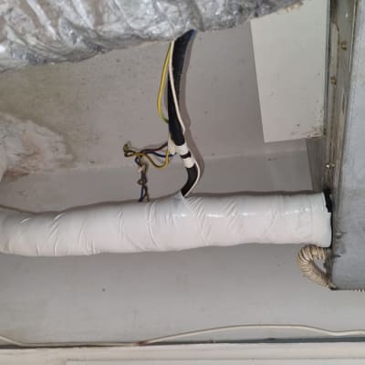 צינור מיזוג אוויר עטוף בבידוד לבן ותקרה עם חוטי חשמל
