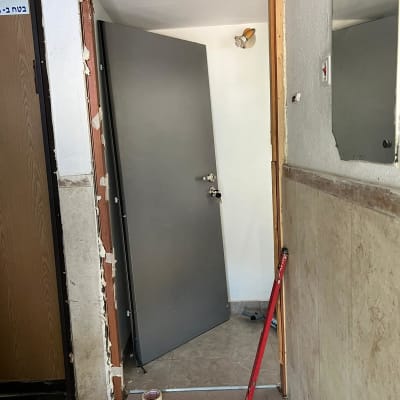 דלת אפורה מותקנת חלקית עם מסגרת עץ חשופה