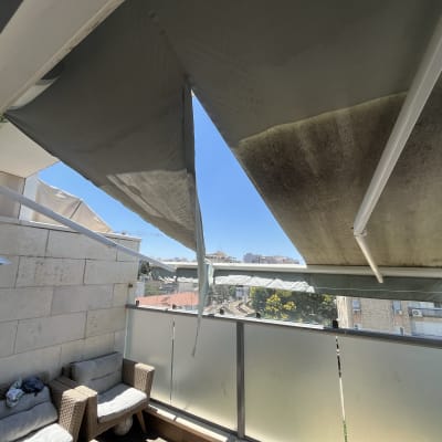 סוכך בד ירוק עם מוטות לבנים במרפסת