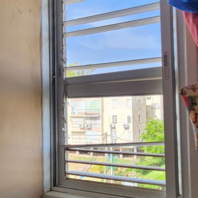 תריסים אופקיים פתוחים בחלון עם וילון צבעוני