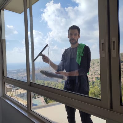 אדם מנקה חלון עם מגב ובד ירוק