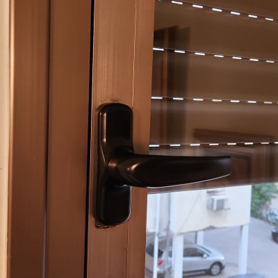 תריסים חומים עם ידית שחורה על חלון