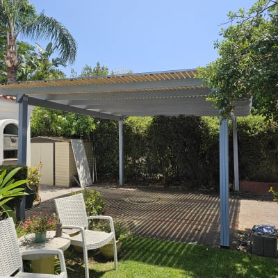 פרגולה בגינה עם כיסאות ושולחן קטן