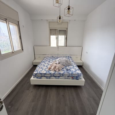 חדר שינה מרוהט צבוע בלבן עם רצפת פרקט