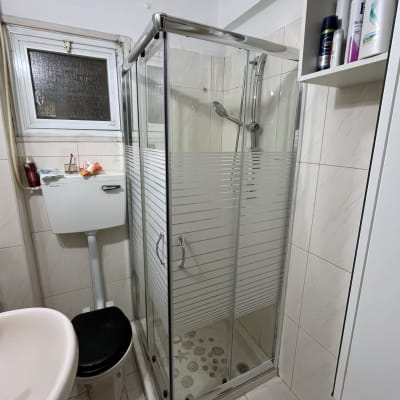 מקלחון זכוכית עם ראש מקלחת ומדף מוצרים