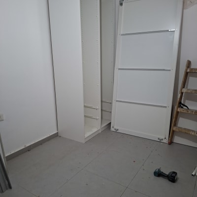 ארון לבן בהרכבה עם מקדחה וסולם בחדר