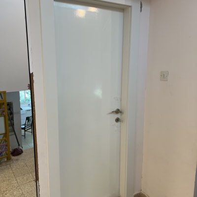 דלת לבנה עם ידית מתכת בחדר פנימי