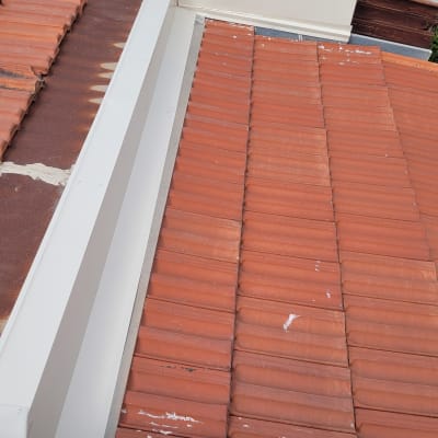 רעפים אדומים על גג עם תעלה לבנה