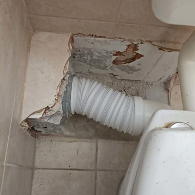 צינור גמיש מחובר לאסלה בקיר שבור