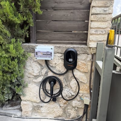 עמדת טעינה לרכב חשמלי מותקנת על קיר אבן בבית פרטי