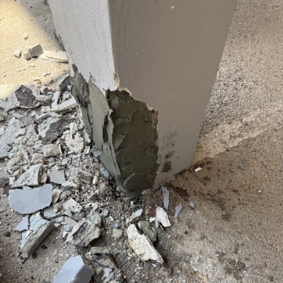 עמוד בטון עם טיח מתקלף והריסות בטון על הקרקע