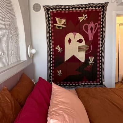 קיר עם שטיח קיר דקורטיבי ומיטה עם כריות צבעוניות