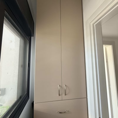 ארון גבוה עם ידיות מתכת ליד חלון ודלת