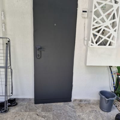 דלת כהה עם ידית שחורה על רקע קיר לבן