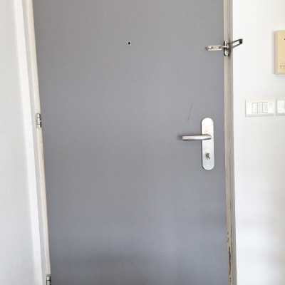 דלת אפורה עם ידית מתכת ובריח עליון