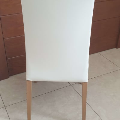 כיסא מרופד בלבן עם רגלי עץ על רצפה מרוצפת