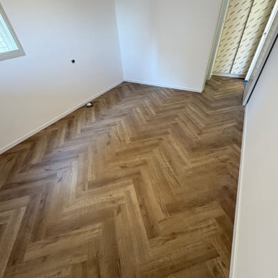 רצפת פרקט מעוצבת בחדר ריק עם קירות לבנים
