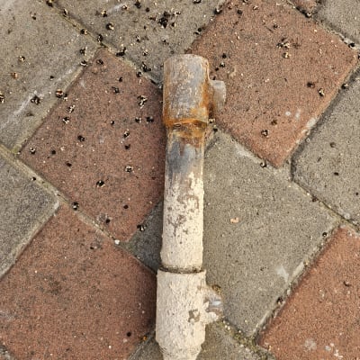 צינור חלוד על רצפת אבנים משתלבות