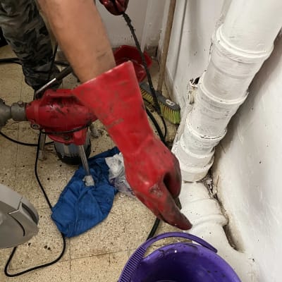 אדם עם כפפות אדומות משתמש בציוד אינסטלציה