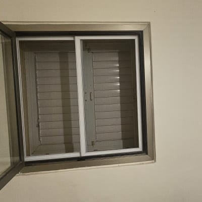 חלון עם תריסים סגורים על קיר לבן