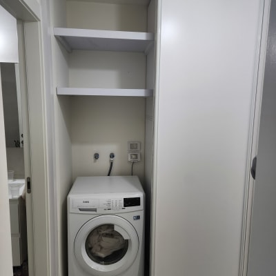 מכונת כביסה בארון עם מדפים מעליה