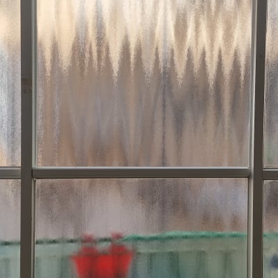 זכוכית מחוספסת עם השתקפות מטושטשת של עצמים אדומים