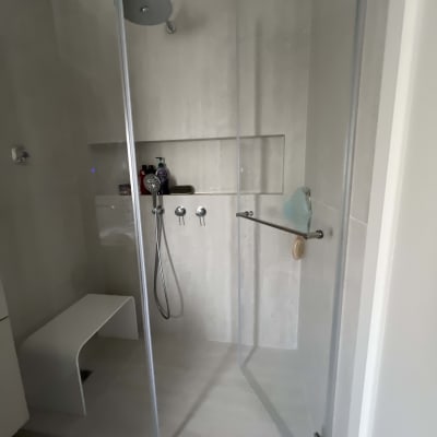 מקלחון זכוכית עם ראש מקלחת ומושב לבן