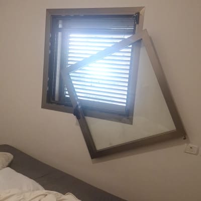 חלון עם תריסים שבורים בחדר שינה